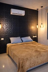 een slaapkamer met een bed met een zwarte muur bij Minimalist City Suite in Chetumal