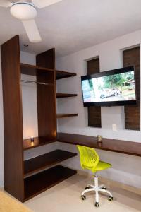 een woonkamer met een gele stoel en een flatscreen-tv bij Minimalist City Suite in Chetumal