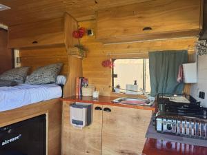 TrapicheFurgoneta camper solo hospedaje sin conducción的拖车里有一张床和一个水槽的厨房
