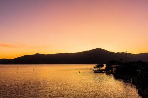 a sunset over a lake with mountains in the background at Pousada Quinta da Margem in Florianópolis