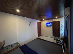 een kamer met een bed en een televisie aan het plafond bij Sabari Stay in Mundakāyam
