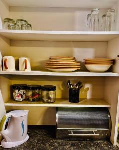 a kitchen shelf with plates and dishes on it at Nalana Guest House in Thaba Nchu +22 photos