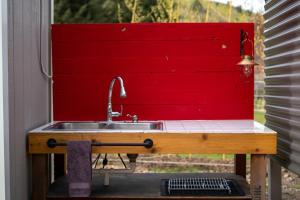 eine Küchenspüle mit einer roten Wand dahinter in der Unterkunft Creek-side Retreat - Glamping in The Dalles