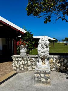 a statue of a lion in front of a stone wall at D O M A I N E - D E - L' A N S E - P I S T O L E T - Proche Grande Vigie, Vue Unique in Anse-Bertrand