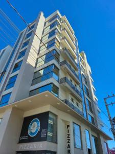 een hoog wit gebouw met een bord erop bij Ap Novo 303! Villa Premium in Piratuba