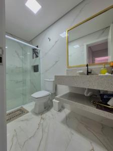 een badkamer met een wastafel, een toilet en een spiegel bij Ap Novo 303! Villa Premium in Piratuba