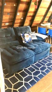 een blauwe bank op een tapijt in een kamer bij Chalé Na coruja e Chalé Encanto com BANHEIRA com AQUECEDOR e hidromassagem 7,5km centro Águas com COM CAFÉ, internet Starlink in Águas de Lindóia