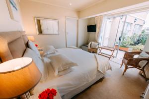 a bedroom with a white bed and a large window at Dolphins' Playground Beachfront B&B in Plettenberg Bay