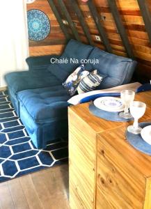 een woonkamer met een blauwe bank en een tafel bij Chalé Na coruja e Chalé Encanto com BANHEIRA com AQUECEDOR e hidromassagem 7,5km centro Águas com COM CAFÉ, internet Starlink in Águas de Lindóia