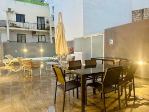 un patio con tavolo, sedie e ombrellone di Central Oasis with Private Pool and Lounge Area a Msida