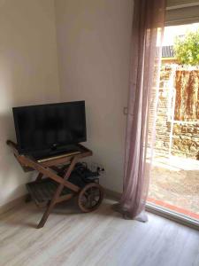 a television on a wooden stand in a room with a window at LES BATTERIES bord de mer in Collioure
