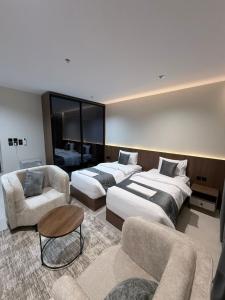 een hotelkamer met twee bedden en een bank bij ديار الاسترخاء للشقق المخدومة in Najran +4 foto's