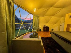 een slaapkamer met een bed en een groot raam bij YOLO Outdoors - Riverside Luxury Domes, Jispa in Jispa
