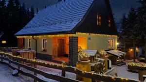 a small house with christmas lights in the snow at Ferienwohnung-direkt-am-Skihang mit Sauna in Kurort Oberwiesenthal