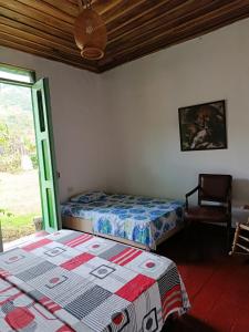 een slaapkamer met twee bedden en een stoel en een raam bij Koniminto in Pijao