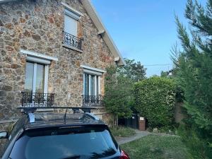 een auto geparkeerd voor een stenen huis bij Rez-de-jardin cozy in Houilles
