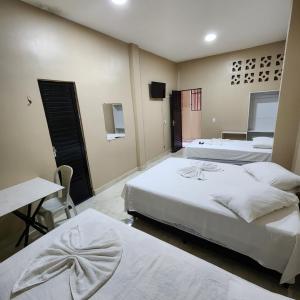 una camera da letto con due letti, un tavolo e una scrivania di Hotel Rocha a Barcarena