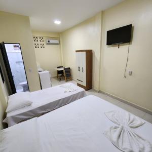 una camera d'albergo con due letti e una televisione di Hotel Rocha a Barcarena