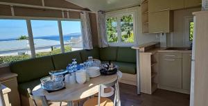 eine Küche mit einem Tisch und einem grünen Sofa in der Unterkunft Camping 4 étoiles - Piscine - ccbegca in Créach-Guennou