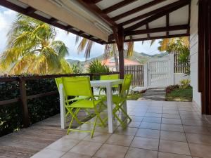 a patio with a white table and green chairs at chez Brigitte et Michel in Les Anses-dʼArlets
