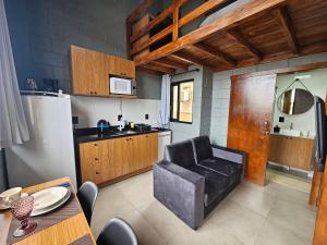 a kitchen with a leather chair and a table and a refrigerator at Residencial Zille - Lofts e Studios in São Miguel dʼOeste