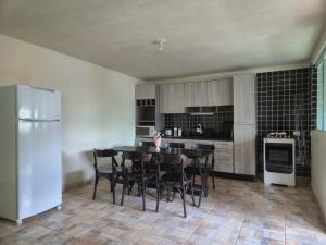 een keuken met een tafel, stoelen en een koelkast bij Hotel Recanto das Pedras in Itapoa