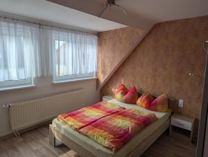 una camera da letto con un letto con un piumone colorato e due finestre di Pension zum Ringelberg a Erfurt Altre 89 foto