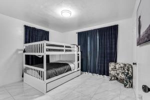- une chambre avec 2 lits superposés et une chaise dans l'établissement Miami Dream Home With 4 Bedrooms Game Room And Backyard Oasis, à North Miami Beach
