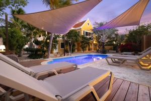 a pool with chairs and an umbrella and a house at Maravia Bonaire in Kralendijk