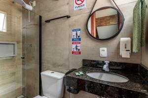 a bathroom with a toilet and a sink and a mirror at Estúdio com ar condicionado próximo ao centro e UDESC CEFID in Florianópolis