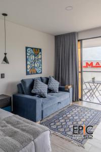 ein Wohnzimmer mit einer blauen Couch und einem Balkon in der Unterkunft Epic Suite 512 Deluxe Airport in Cuba