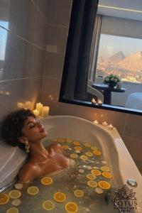 a woman laying in a bath tub with a window at Lotus signature hotel in Cairo +49 photos