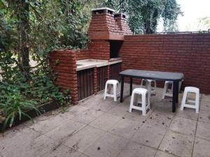 a table and two stools next to a brick wall at PH con cochera cubierta cerca de la playa in Villa Gesell