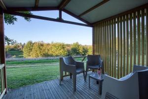 a deck with chairs and a table with a view of a field at ZEcamping 3 étoiles familial do friendly piscine chauffée restaurant et bar in Les Eyzies-de-Tayac