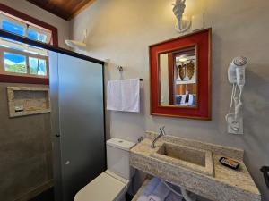 een badkamer met een toilet, een wastafel en een spiegel bij Vila Bella Suítes - Conforto no Centro in Carrancas