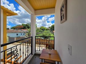 een kamer met een balkon met een tafel en uitzicht bij Vila Bella Suítes - Conforto no Centro in Carrancas