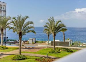 a view of a resort with palm trees and the ocean at Madeira Palace Ocean View in Funchal