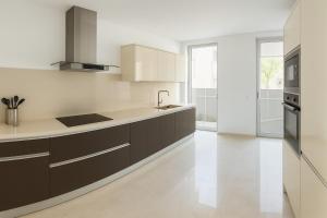a kitchen with white walls and brown cabinets at Madeira Palace Ocean View in Funchal