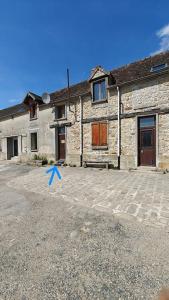 a stone building with a blue arrow in front of it at Le studio Mauperthuis in Forges
