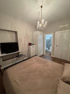 een slaapkamer met een bed, een televisie en een kroonluchter bij Ai Cappuccini in Tricarico