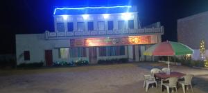 a table with chairs and an umbrella in front of a building at Shiv Shakti Hotel And Resort in Mākundgarh +1 photo