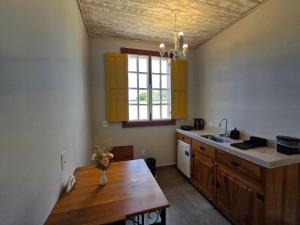 een keuken met een houten tafel en een raam bij Vila Bella Suítes - Conforto no Centro in Carrancas +30 foto's