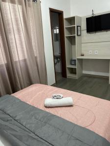 een bed met een roze dekbed met een handdoek erop bij H L Hotel in Pelotas
