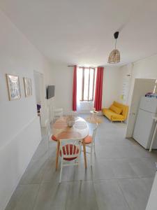 a kitchen and living room with a table and chairs at L'Orangerie du Domaine F3 in Forges