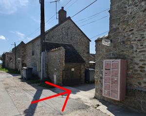 a red arrow is standing next to a brick building at L'Orangerie du Domaine F3 in Forges