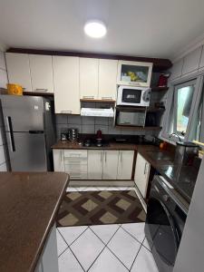 een keuken met witte kasten en een roestvrijstalen koelkast bij Apartamento inteiro 45m, centro, com garagem in Torres