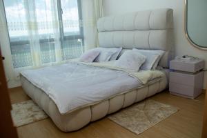 a bedroom with a white bed with a large window at Skyline Luxury 17th-Floor 1BR near Junction Mall - City Views, Pool, Gym & Full-Body Massage Chair in Nairobi +44 photos