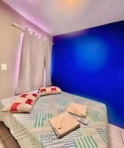 a bed in a room with a blue wall at Thebluee Matinhos beach in Matinhos