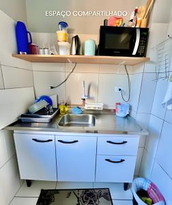 a small kitchen with a sink and a microwave at Thebluee Matinhos beach in Matinhos
