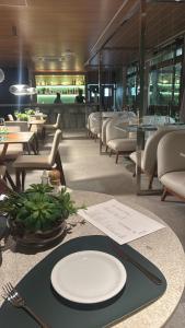 een restaurant met witte borden op een tafel met stoelen bij Beach Class Verano Muro Alto in Porto De Galinhas